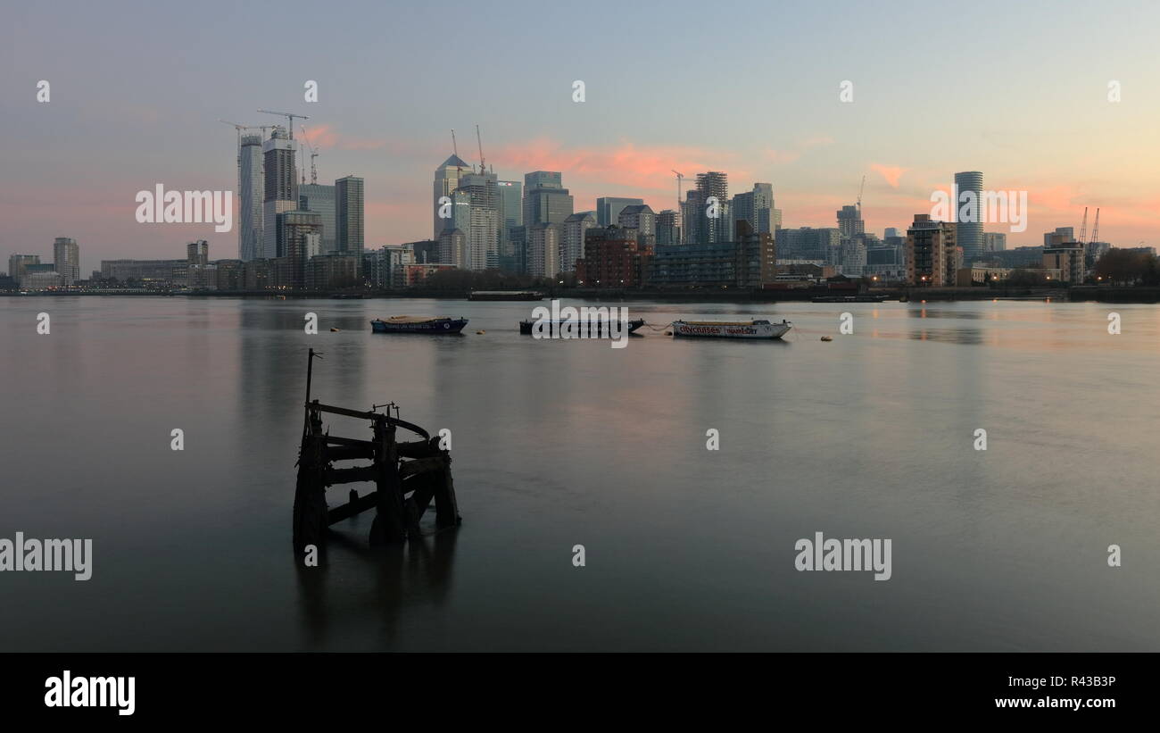 La mattina presto sul lato della Groenlandia accanto alla Marina Sud Dock con una bella vista al Canary Wharf area. Riverside acqua tranquilla con bella riflessioni. Foto Stock