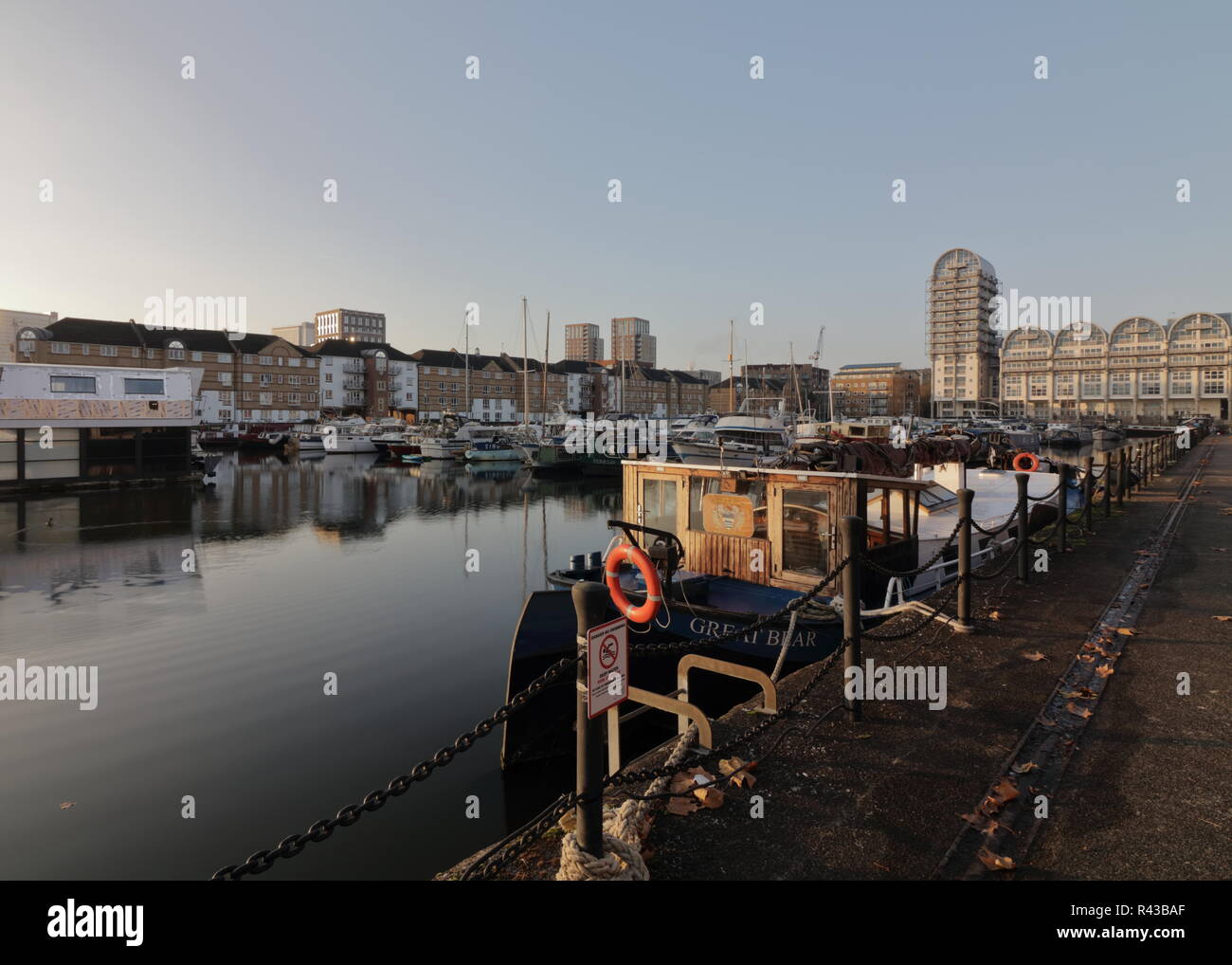 La mattina presto in Sud Dock area marina a Londra con barche parcheggiate e bella riflessioni sull'acqua. Pulire e il cielo sereno, verso la fine di novembre. Foto Stock