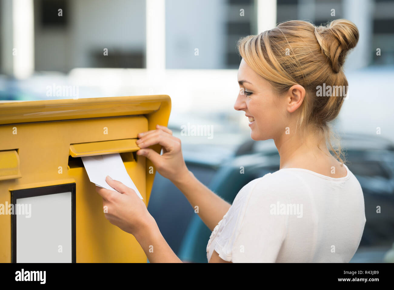 Donna inserendo la lettera nella cassetta postale Foto Stock