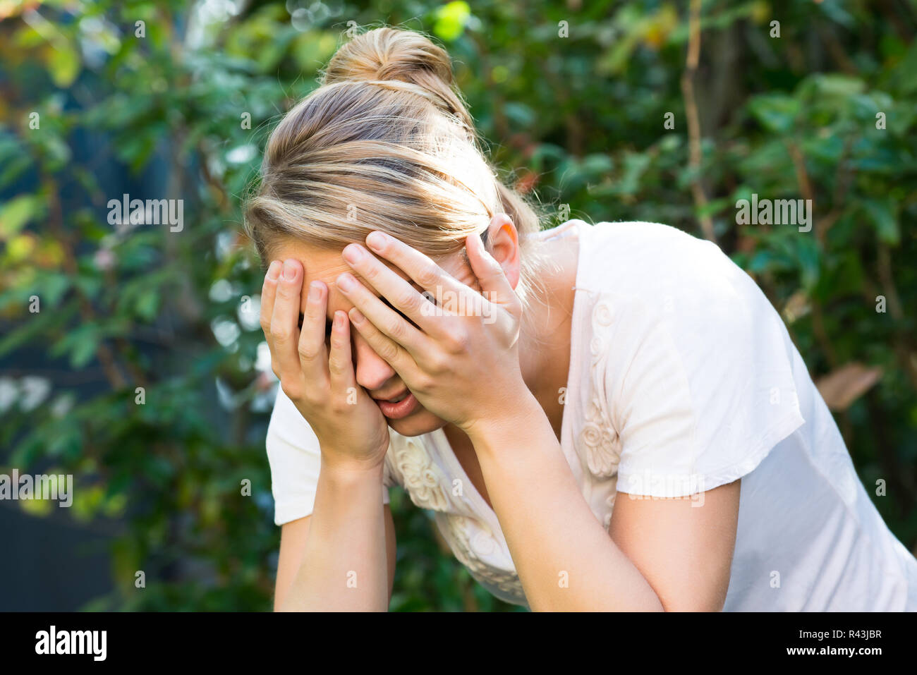 Donna che ricopre la faccia con le mani Foto Stock