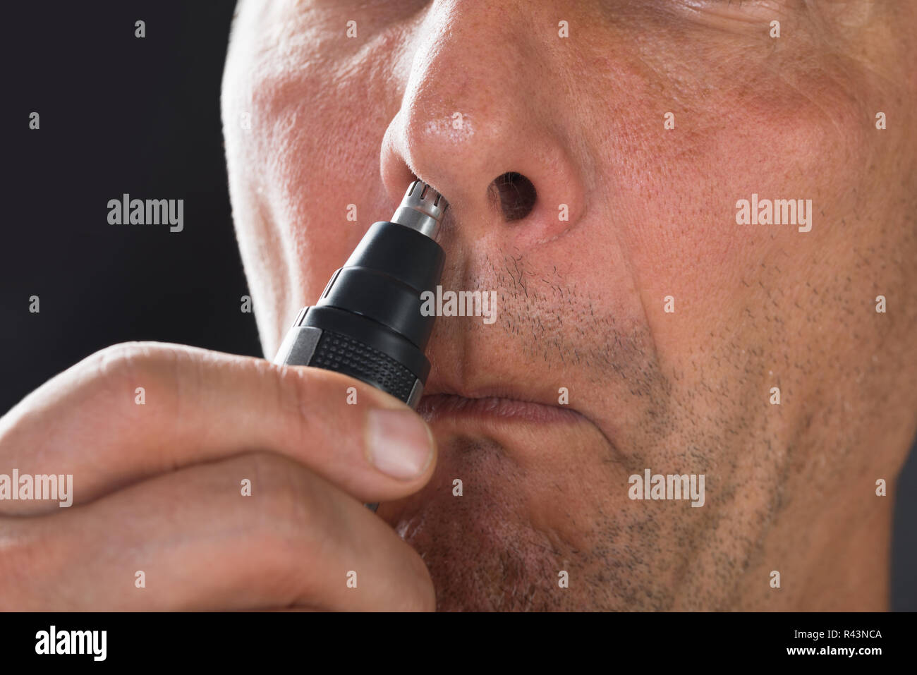 L'uomo rimuovere i peli dal naso con trimmer Foto stock - Alamy
