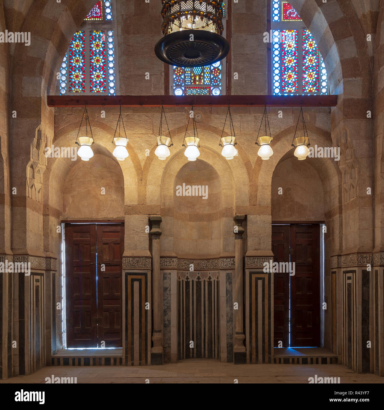 Parete di marmo con mihrab (nicchia), due porte in legno, grandi archi e finestre di vetro macchiate in moschea attaccata alla Bek Khayer Mausoleo, Darb Al-Ahmar dis Foto Stock