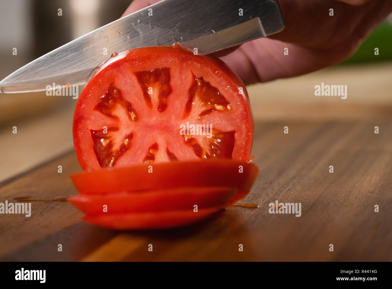 Primo piano di affettatura pomodoro maturo con il coltello sul tagliere Foto Stock