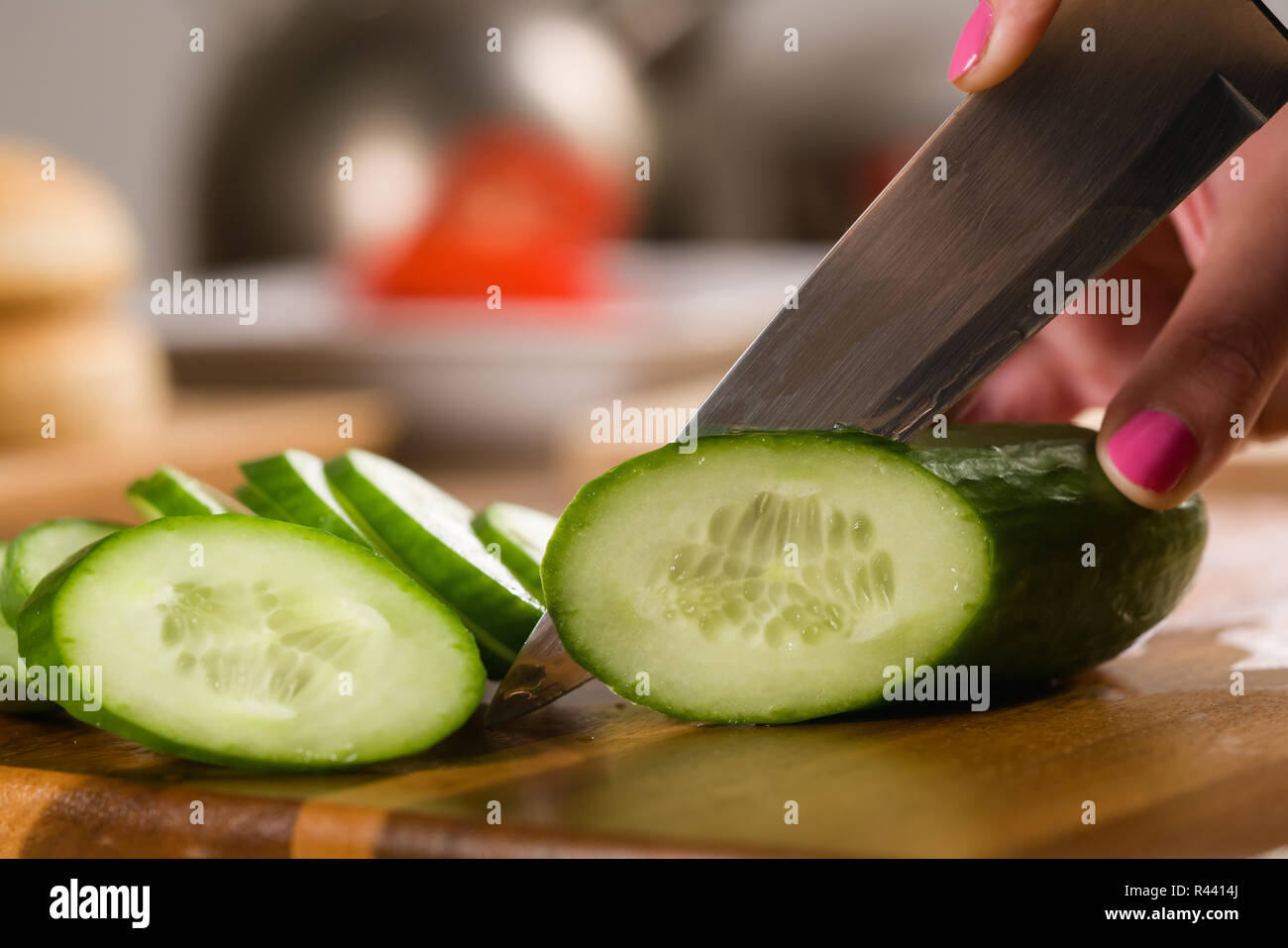 Primo piano della maturazione per affettare il cetriolo con il coltello sul tagliere Foto Stock