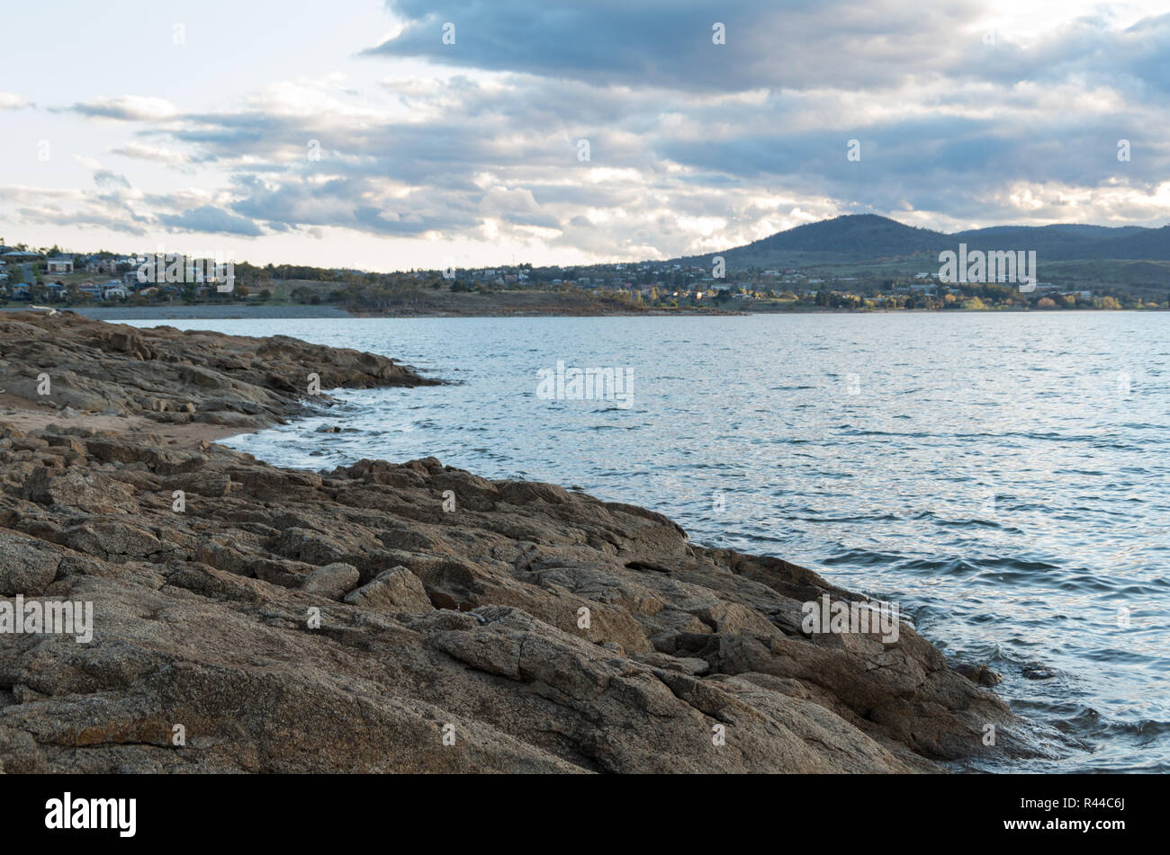 Tramonto sul lago Jindabyne & montagne innevate su un pomeriggio nuvoloso Foto Stock