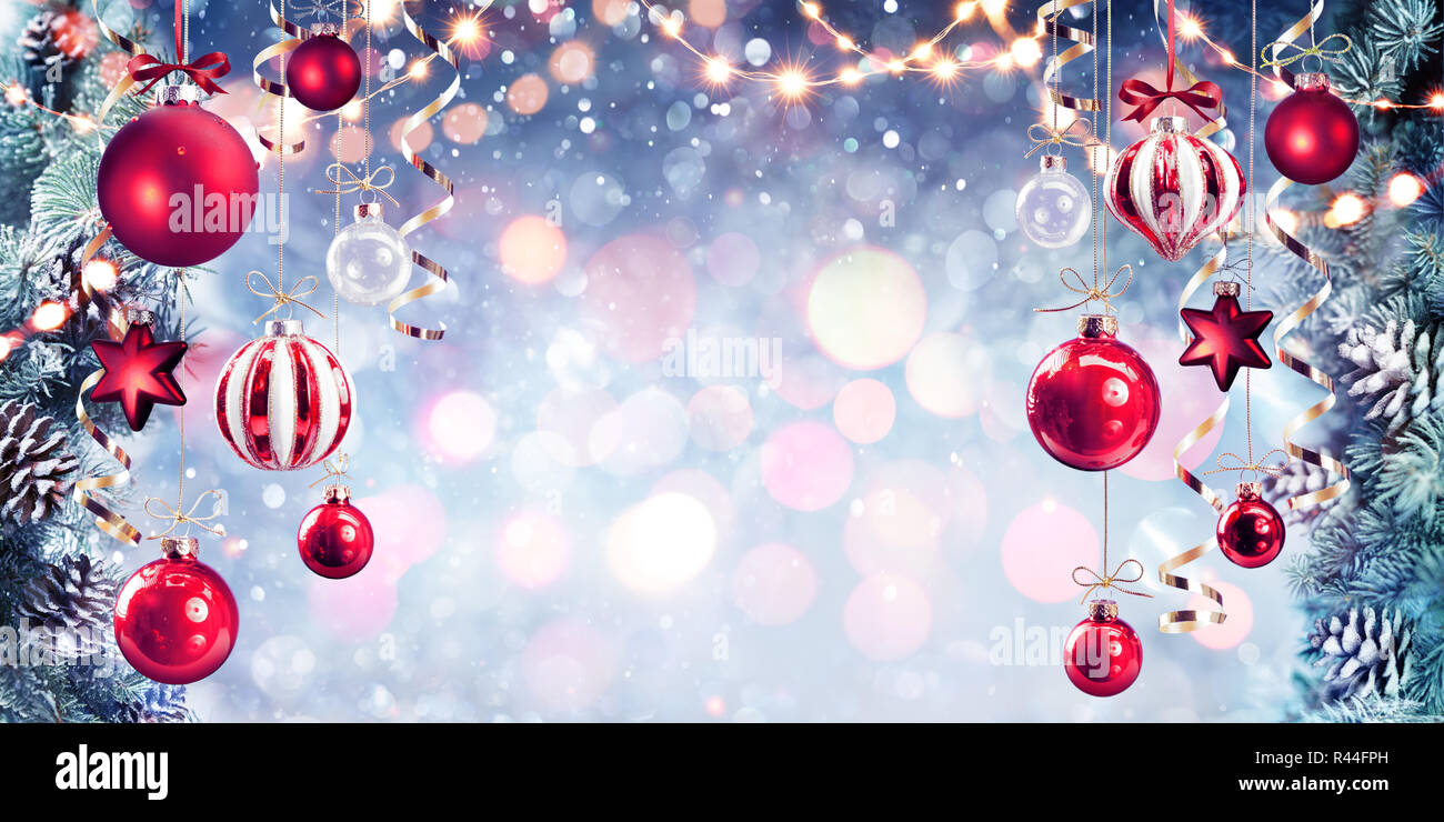 Natale - Rosso Baubles appeso con rami di abete in sfondo lucido Foto Stock