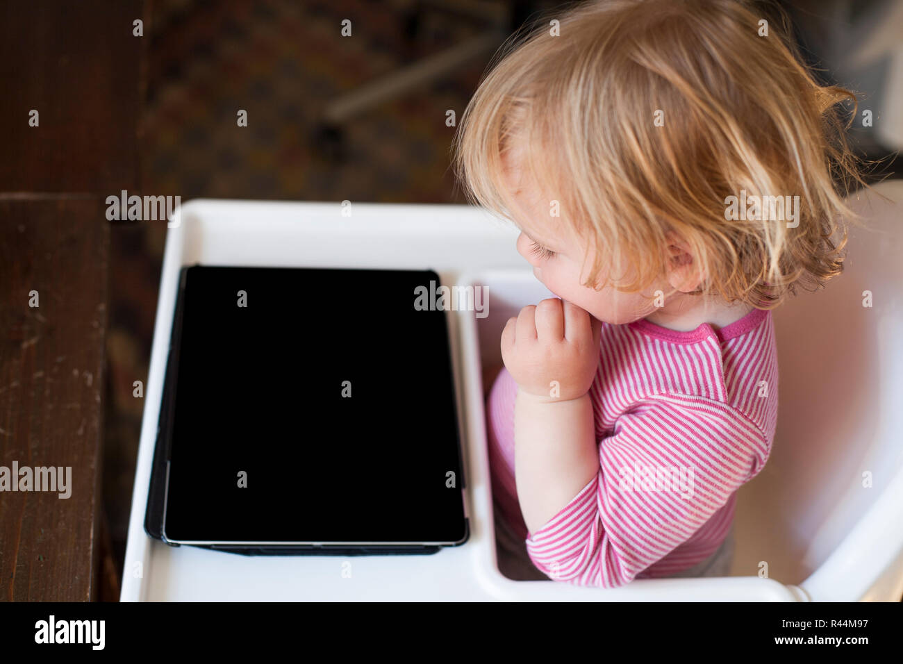 Blonde baby guardando lo schermo è vuoto tablet Foto Stock