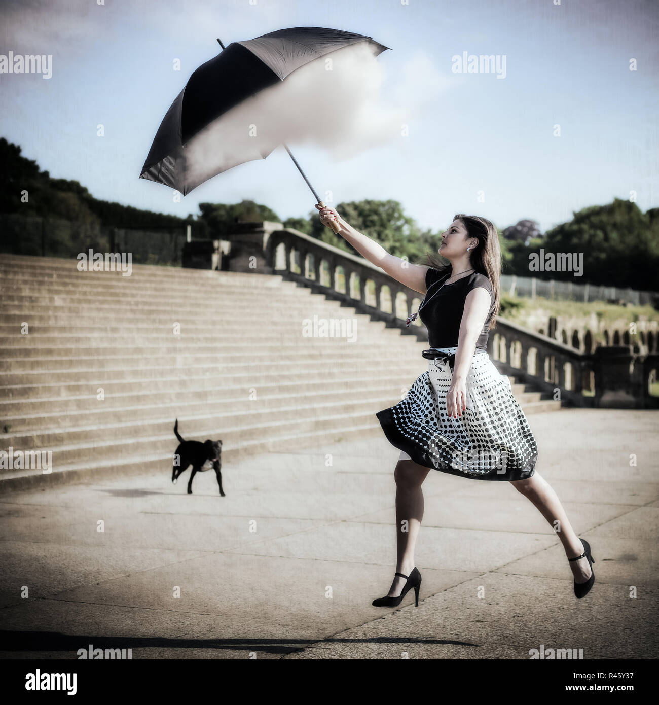 La donna il salto e la cattura di Cloud con ombrellone Foto Stock