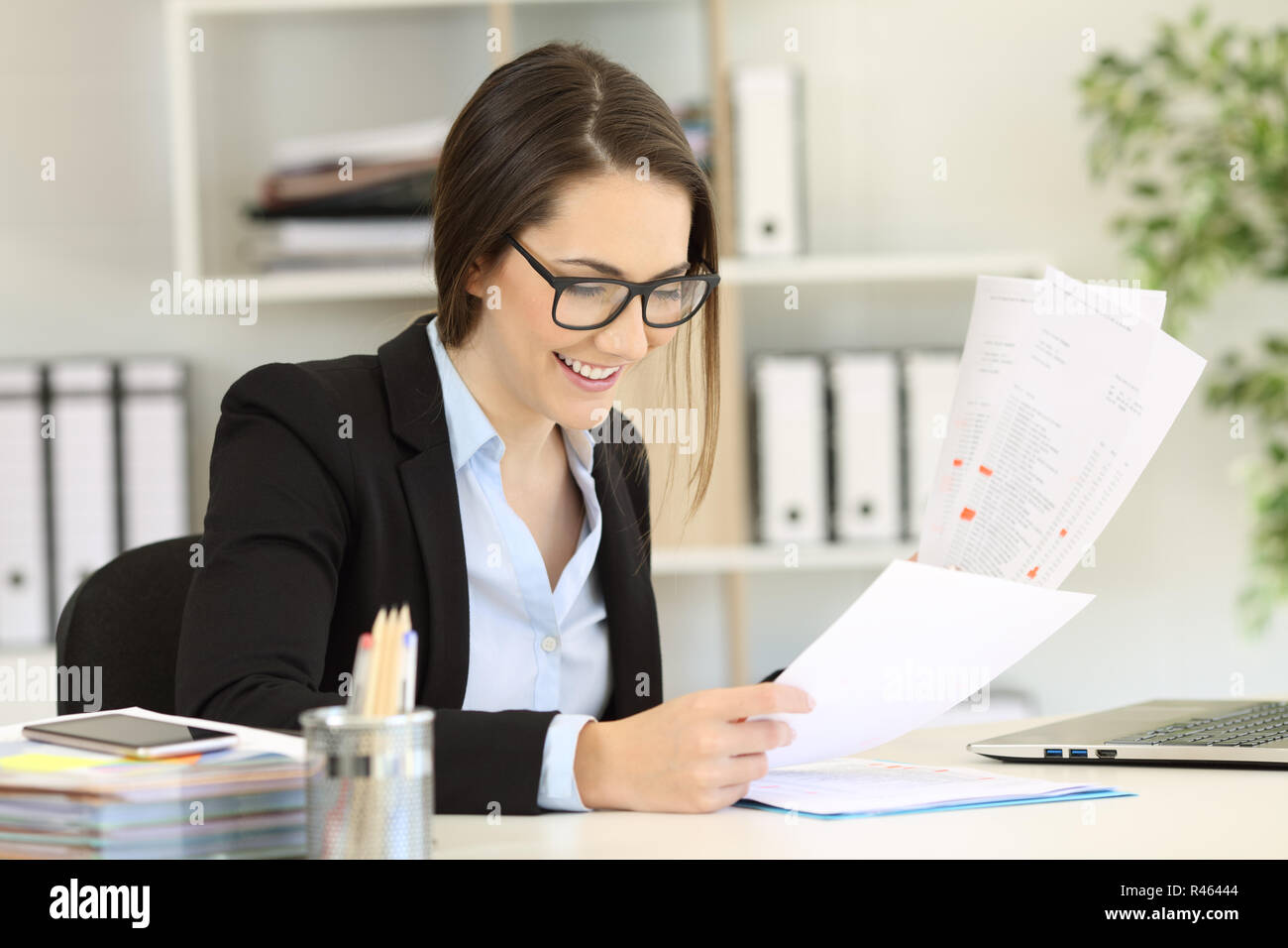 Felice lavoratore di ufficio indossando occhiali confrontando i documenti su carta Foto Stock