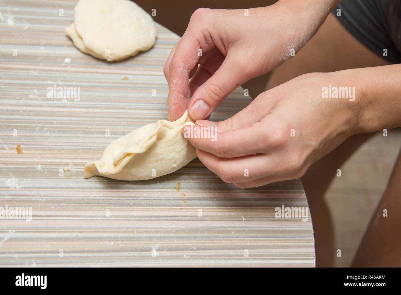 Mani femminili fissare la cucitura torta sul tavolo della cucina Foto Stock