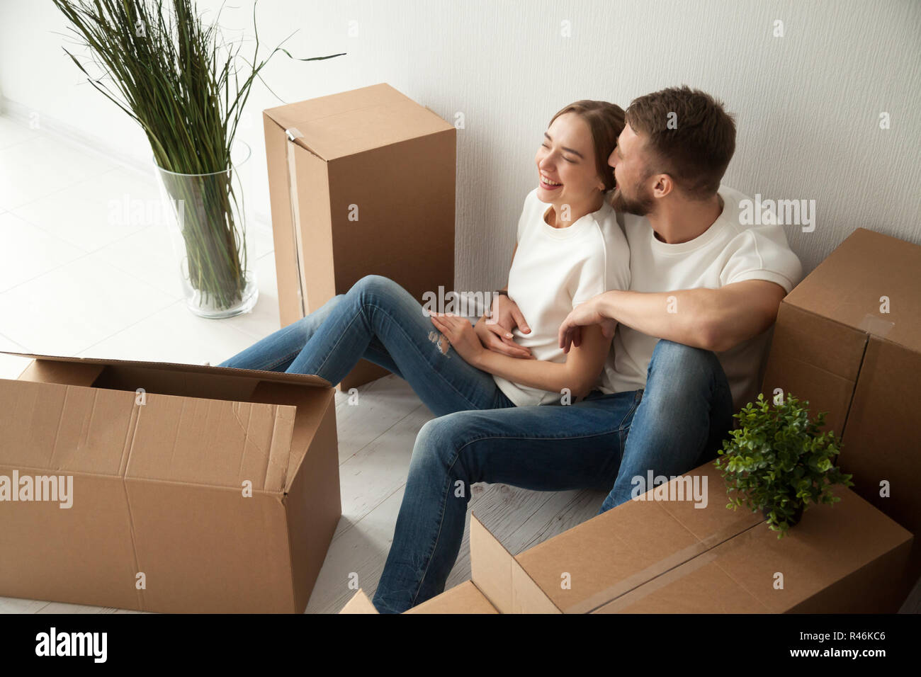 I giovani di ridere giovane seduto sul pavimento in un nuovo appartamento Foto Stock
