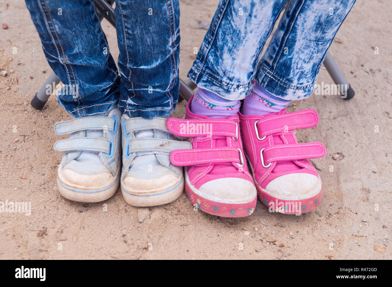 Close-up di due coppie di bambini&#39 s piedi vestiti in jeans e scarpe da ginnastica Foto Stock