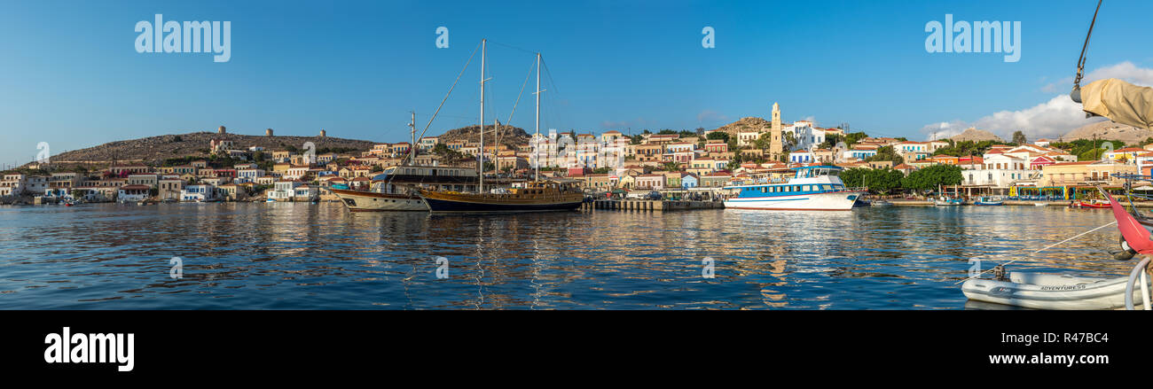 Le case tradizionali e le barche nel porto dell'isola greca di Chalki nel Dodecaneso mare. Foto Stock