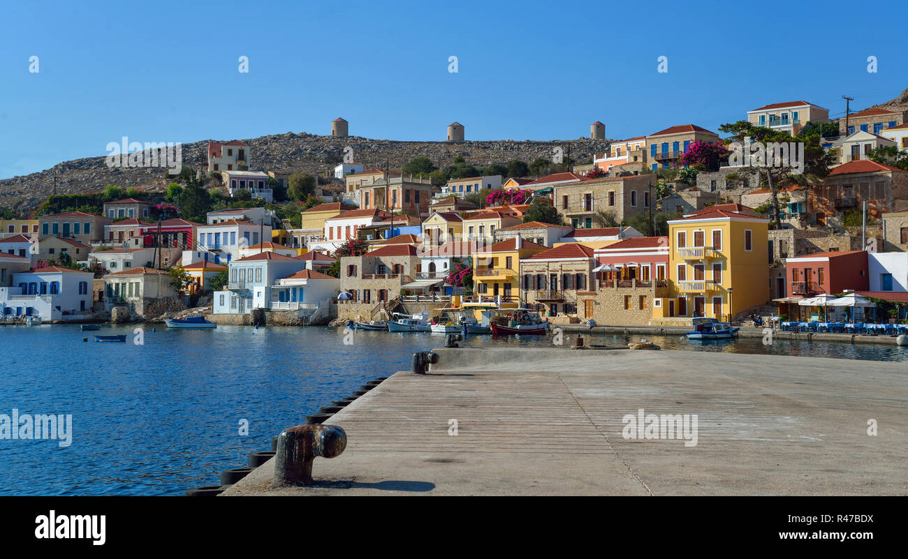 Le case tradizionali e le barche nel porto dell'isola greca di Chalki nel Dodecaneso mare. Foto Stock