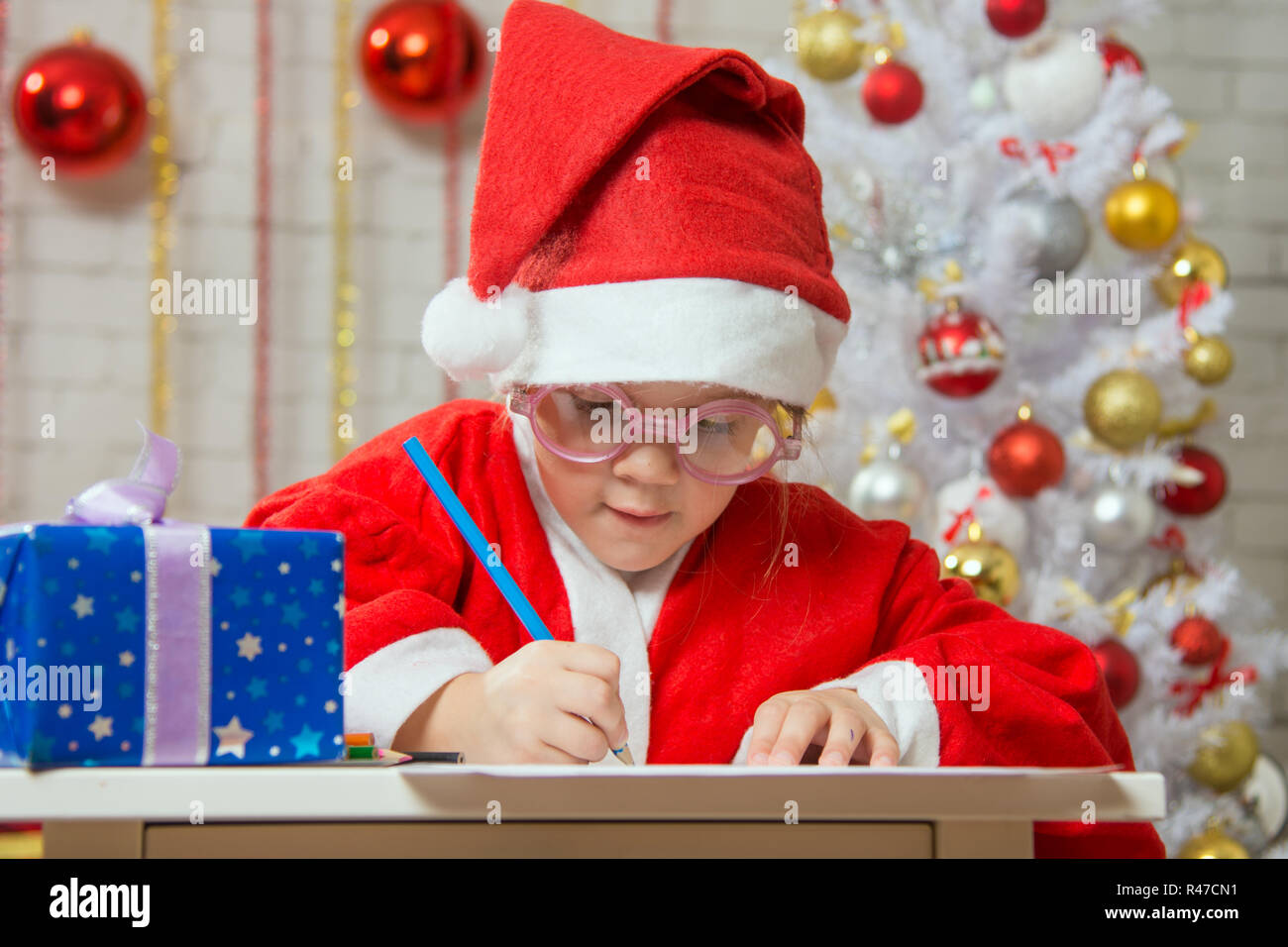 La ragazza si prepara con entusiasmo una carta regalo per Natale Foto Stock