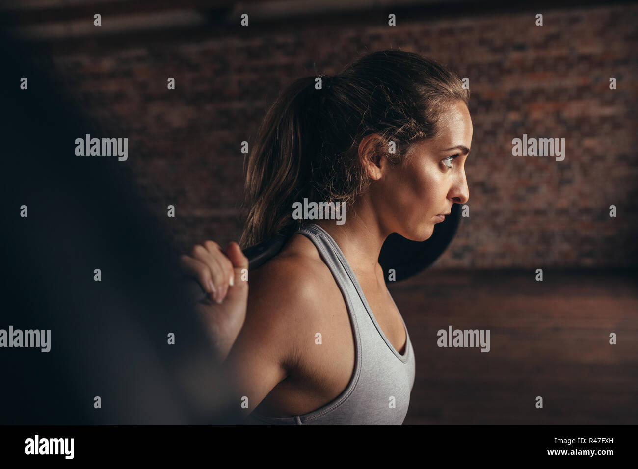Un sano giovane donna alla palestra esercitando con barbell. Montare la giovane donna che lavora fuori con pesi pesanti a cross training gym. Foto Stock