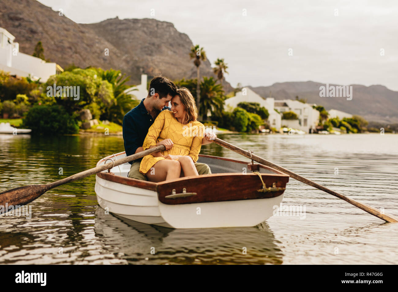 Coppia giovane godendo la loro barca data in un lago. Matura in amore seduti insieme in una barca di toccare le loro teste guardando ogni altro. Foto Stock