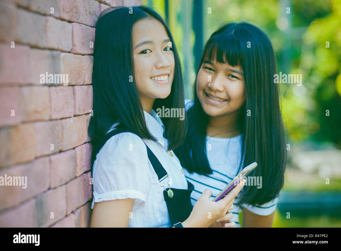 Due asian adolescente toothy volto sorridente con felicità emozione holdhing smartphone a portata di mano Foto Stock