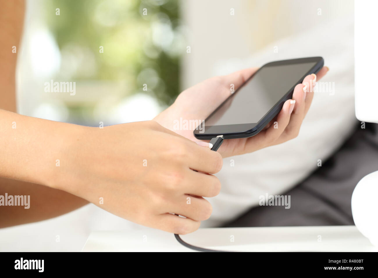 Donna mani collegando un caricabatterie in uno smart phone Foto Stock