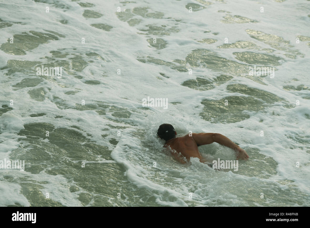 Durban, KwaZulu-Natal, Sud Africa, singolo adulto maschio nuotatore mare tirando stesso attraverso l'acqua aperta con potenti colpi di braccio Foto Stock