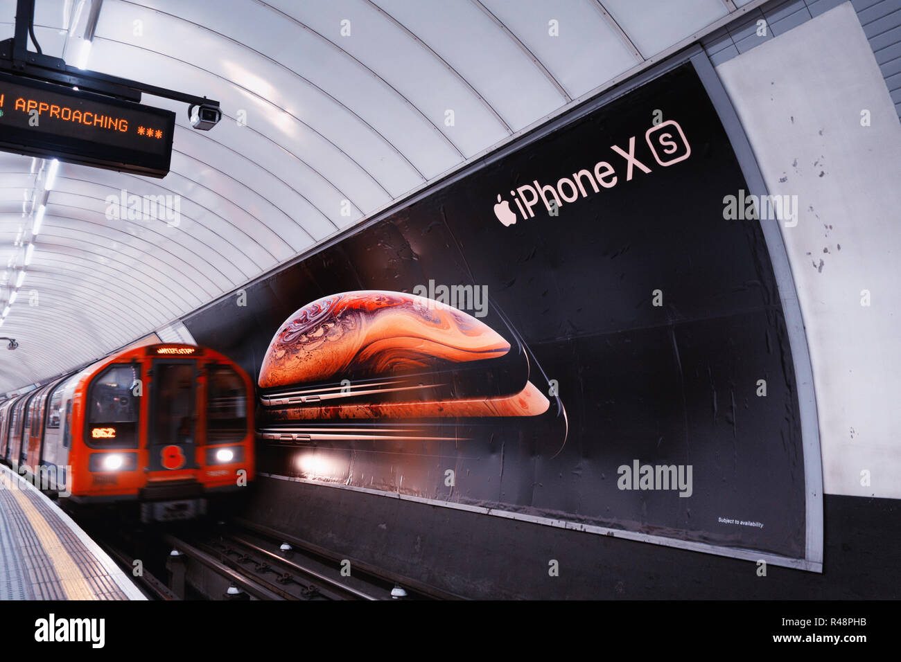 Tubo treno passa ad un poster per il nuovo Apple iPhone XS, poster pubblicitario nella metropolitana di Londra via Foto Stock
