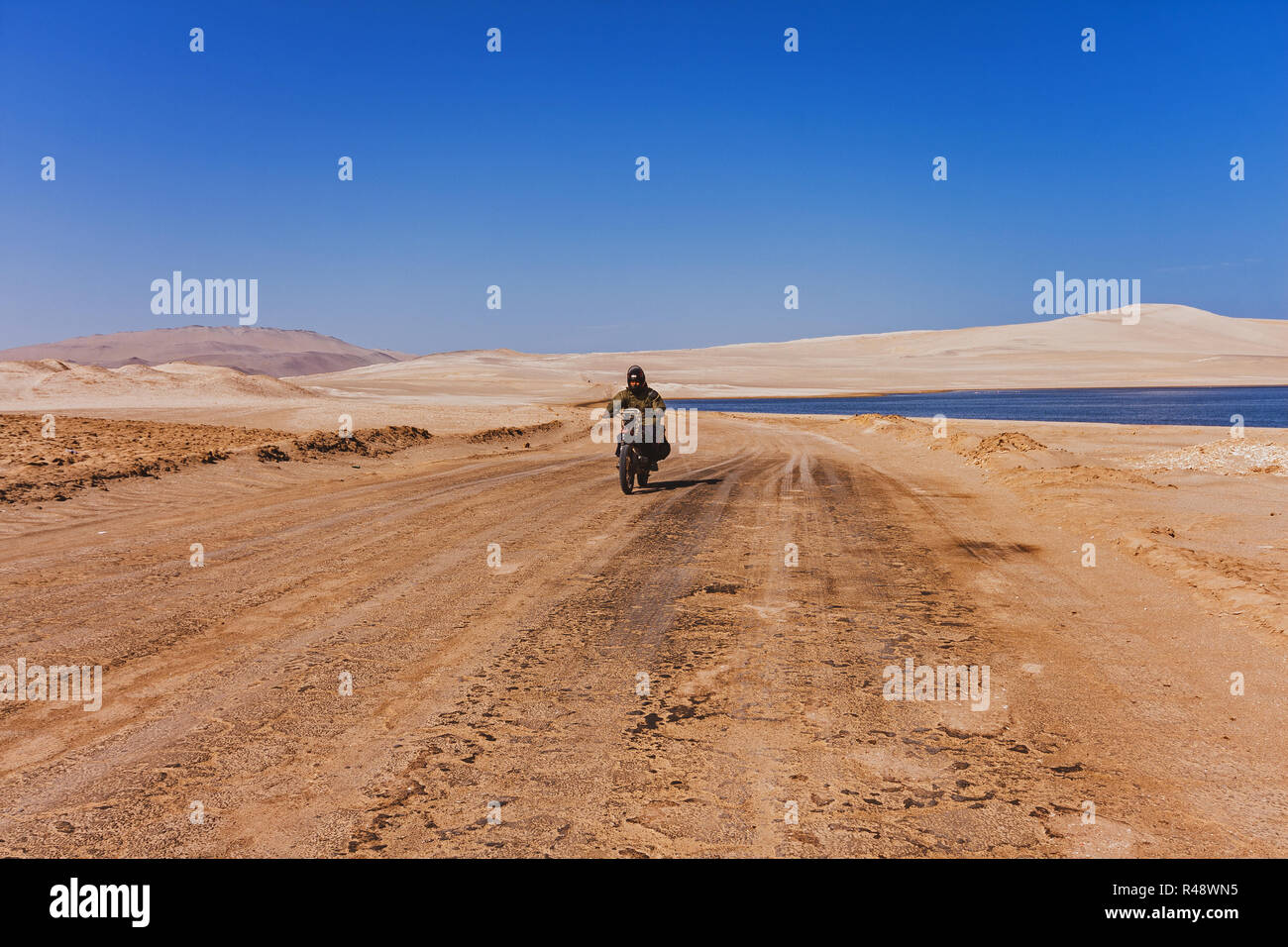 Uomo alla guida di una moto nel deserto di strade di paracas al mattino Foto Stock