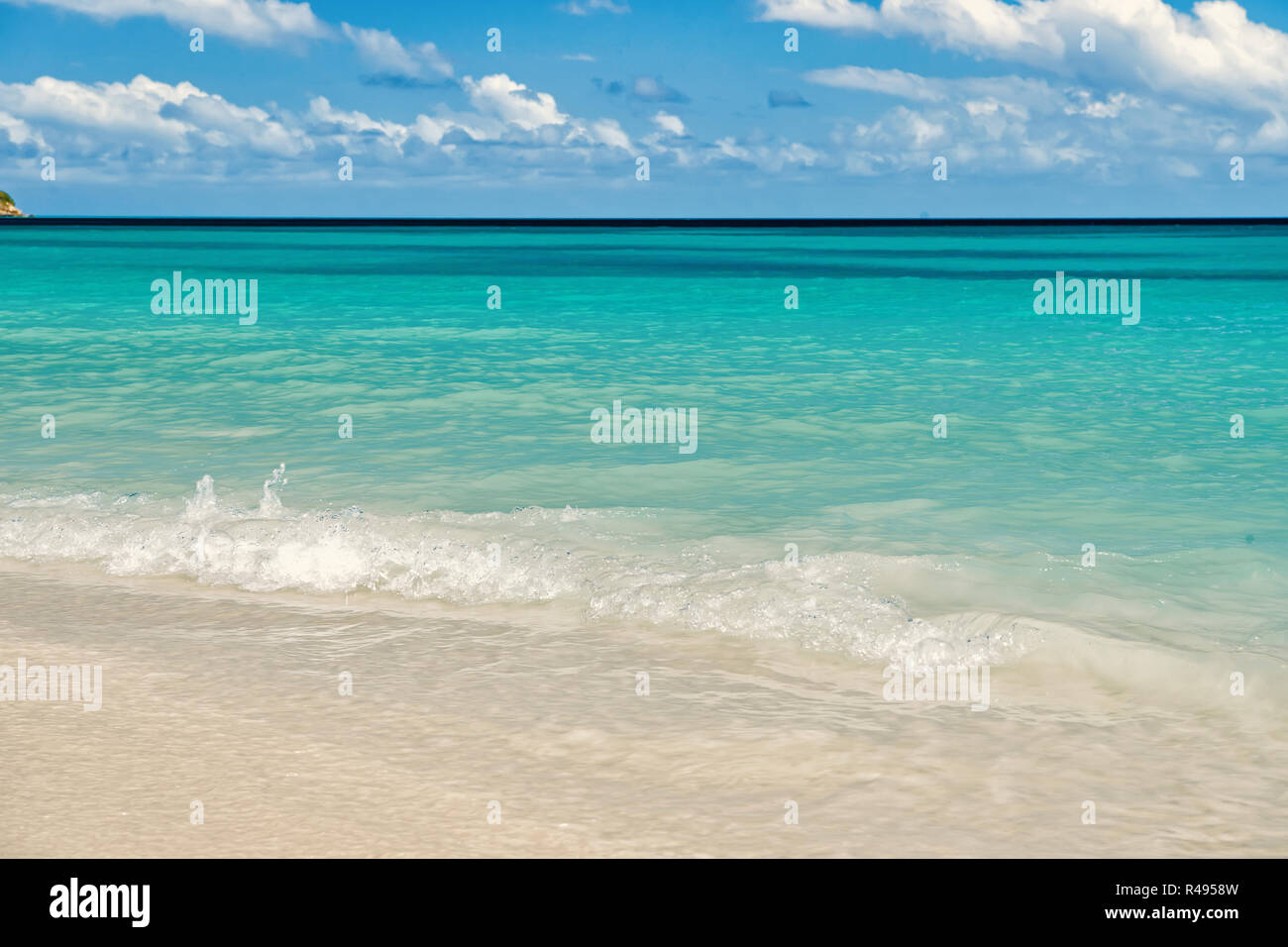 Mare o oceano spiaggia con sabbia bianca e acqua turchese onde in st Johns, Antigua. Seascape sulla giornata di sole su nuvoloso cielo blu sullo sfondo. Estate, vacanze, Foto Stock