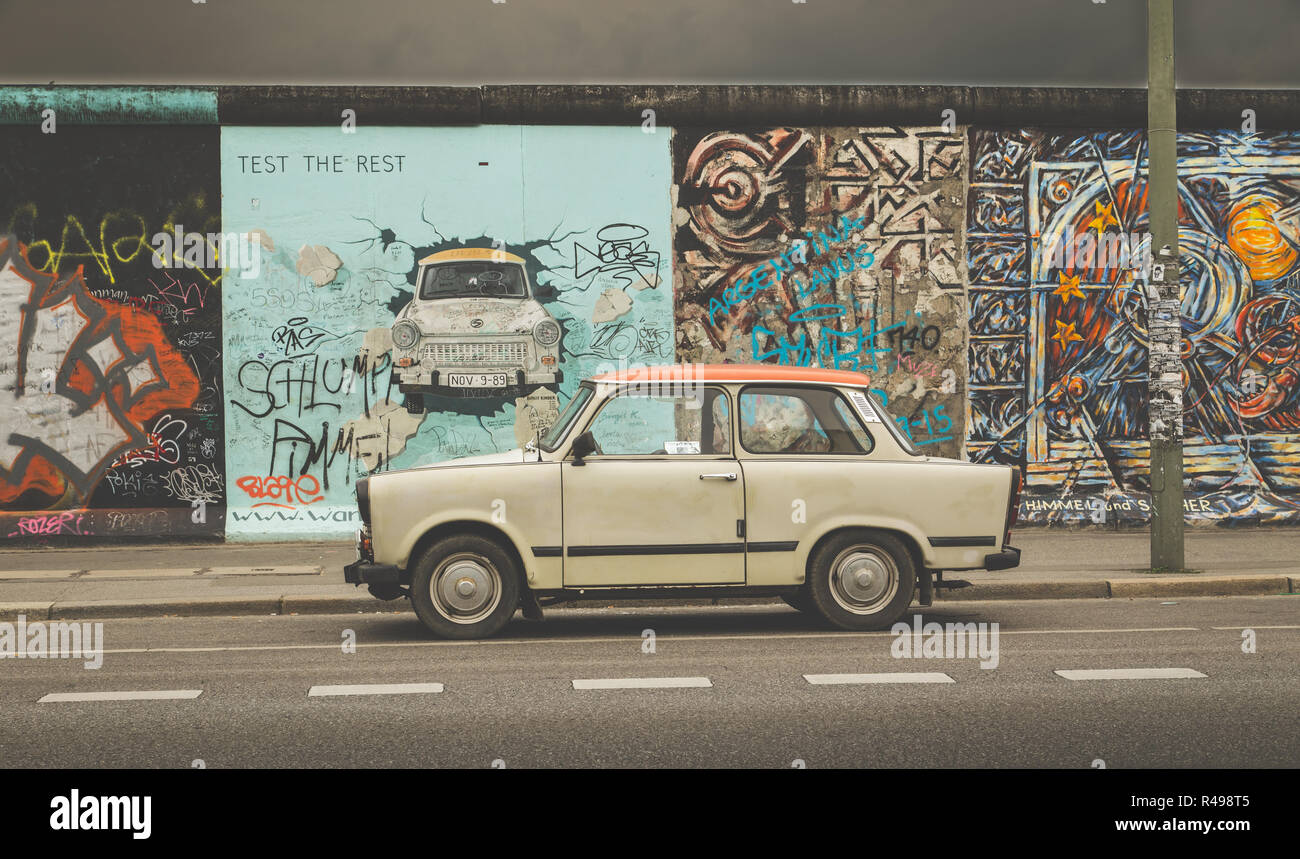 Famosa Berliner Mauer (Berlino) Parete a East Side Gallery con una vecchia Trabant, il più comune veicolo utilizzato in Germania est di Berlino, Germania Foto Stock