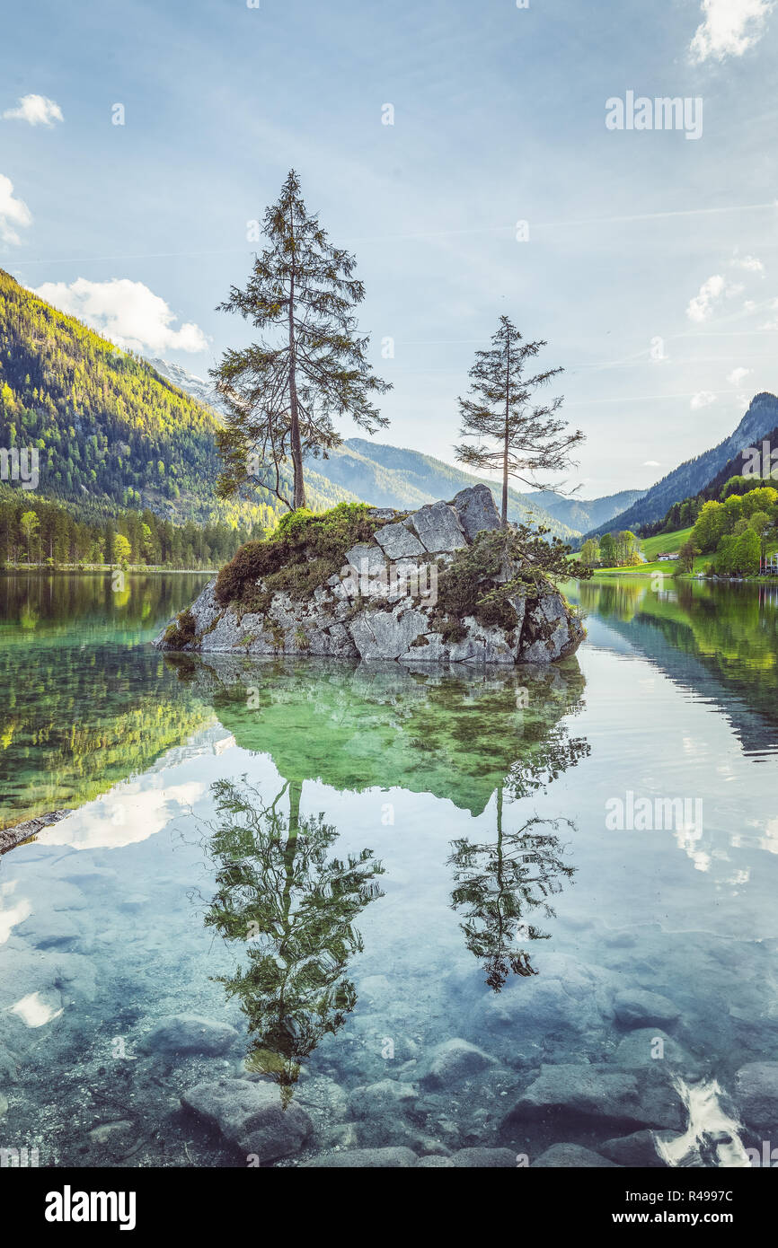Bellissima scena di alberi su un isola di roccia in uno scenario idilliaco presso l'incantevole lago di Hintersee con cielo blu e nuvole in estate Nationalpark Berchtesgaden Foto Stock