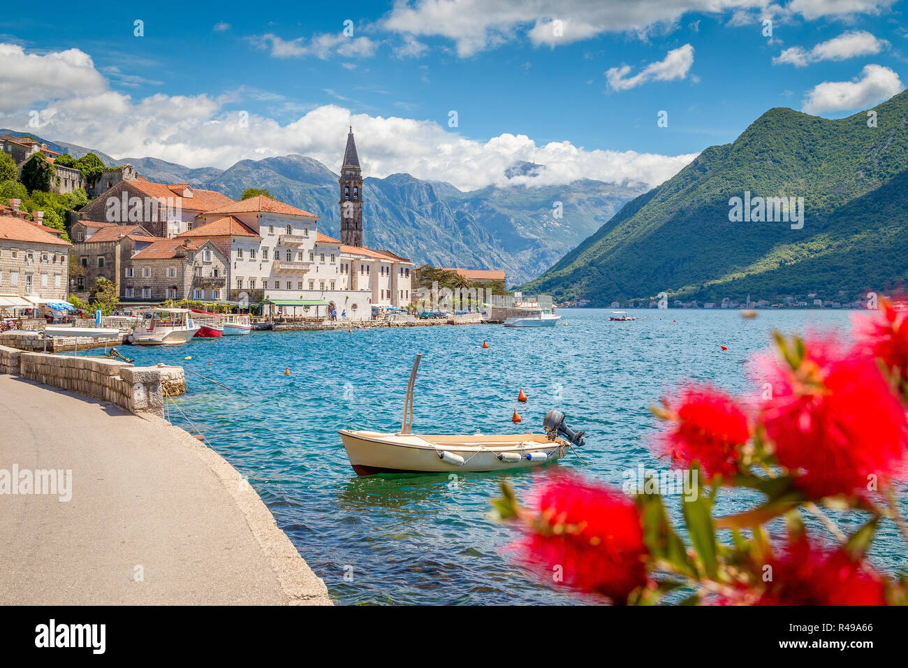 Città storica di Perast alla famosa Baia di Kotor con fiori che sbocciano in una bella giornata di sole con cielo blu e nuvole in estate, Montenegro, Balcani Foto Stock