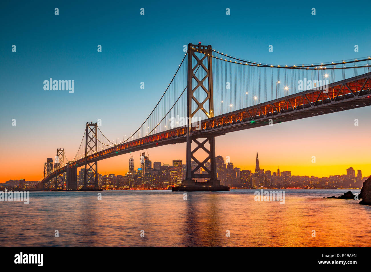 Classic vista panoramica dello skyline di San Francisco con il famoso Oakland Bay Bridge illuminato nel bellissimo golden luce della sera al tramonto in estate Foto Stock