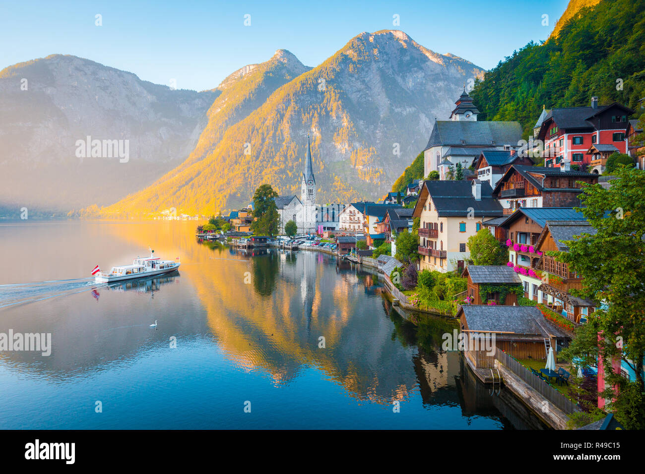 Classic vista da cartolina famosa Hallstatt Lakeside Town nelle Alpi con tradizionale nave passeggeri all'inizio. La luce del mattino al sorgere del sole su una bella d Foto Stock