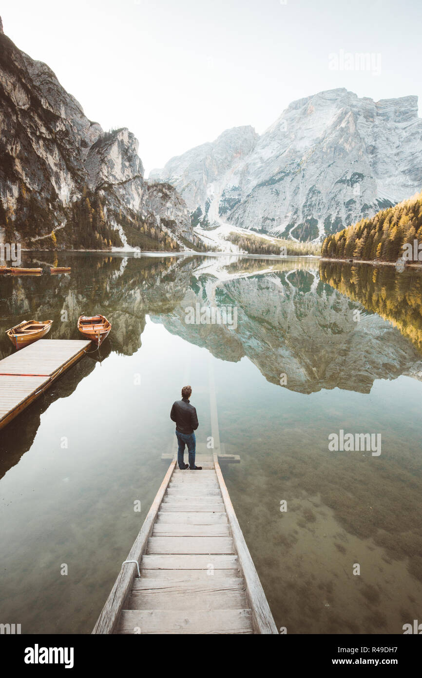 Bellissima vista di un giovane uomo in piedi sulle scale di legno a guardare il tramonto al famoso Lago di Braies Dolomiti, Alto Adige, Italia Foto Stock