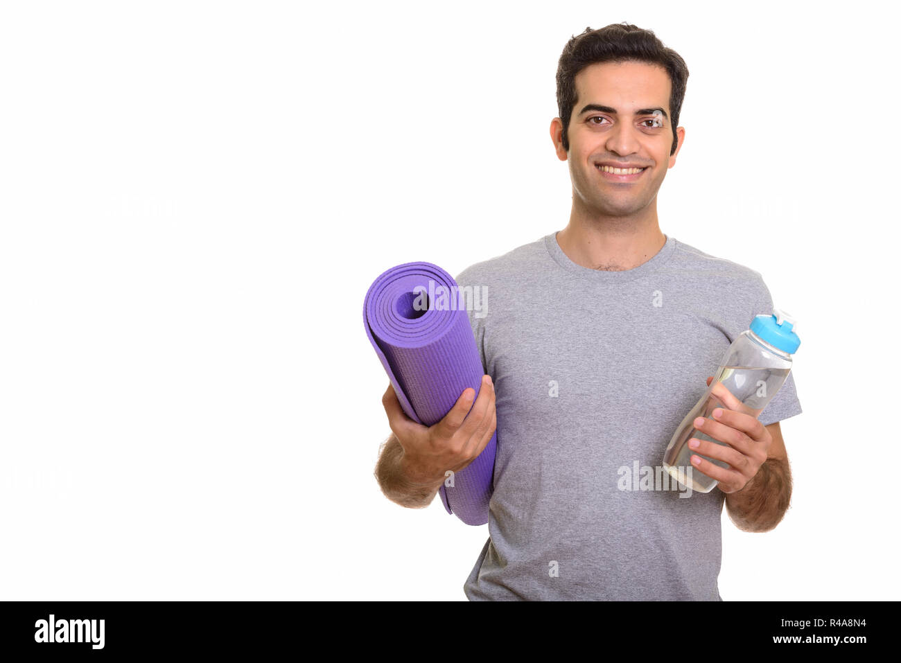 Giovani felici persiano di uomo con materassino yoga e una bottiglia d'acqua pronta Foto Stock