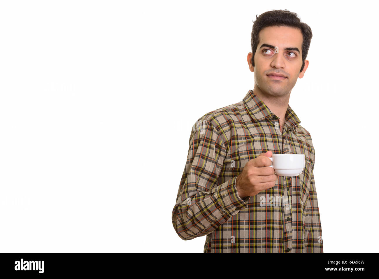 Giovane uomo persiano pensando tenendo tazza da caffè Foto Stock