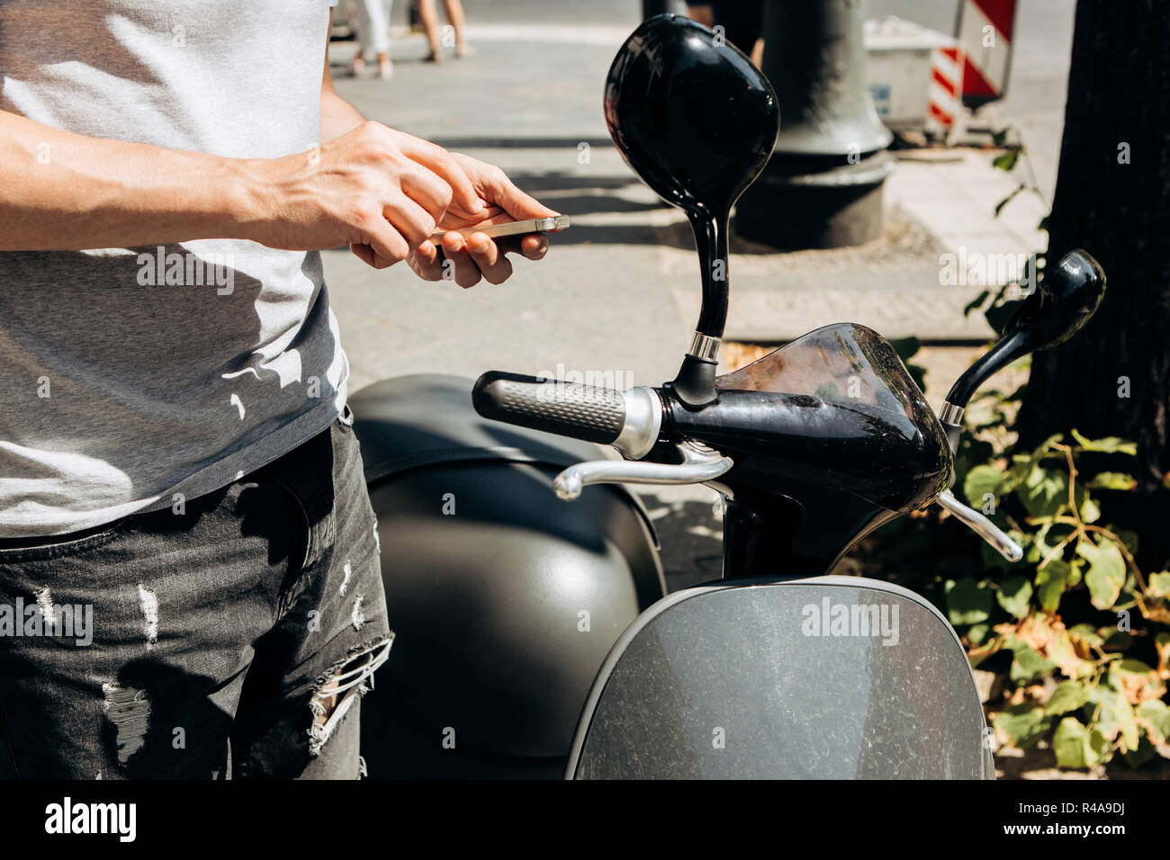 Un ragazzo o un turista attiva o Noleggia uno scooter elettrico utilizzando un'applicazione mobile su un telefono cellulare per viaggiare in giro per la città. Lo scooter elettrico è un veicolo popolare a Berlino in Germania. Foto Stock