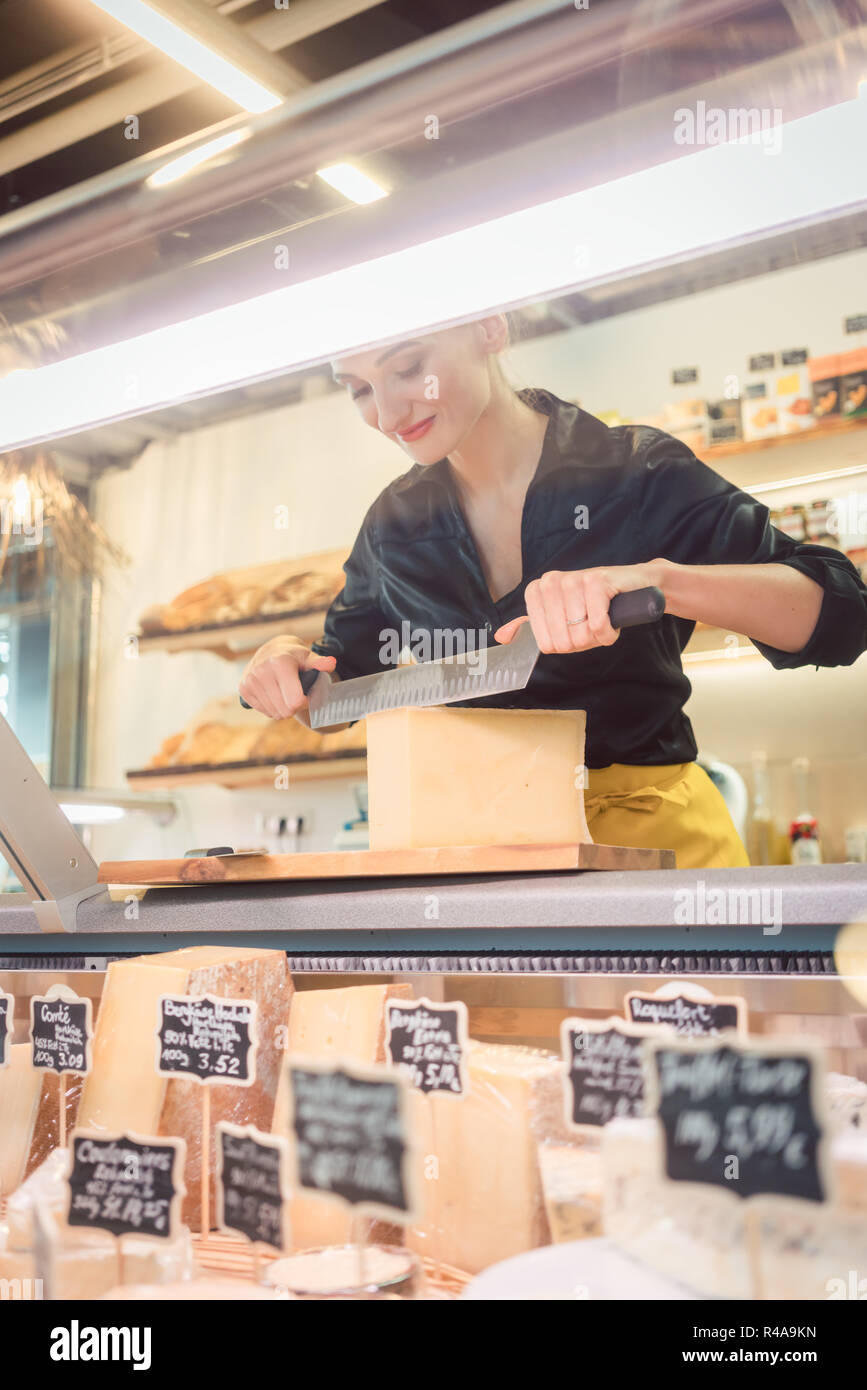 Giovane commessa di deli formaggio da taglio Foto Stock