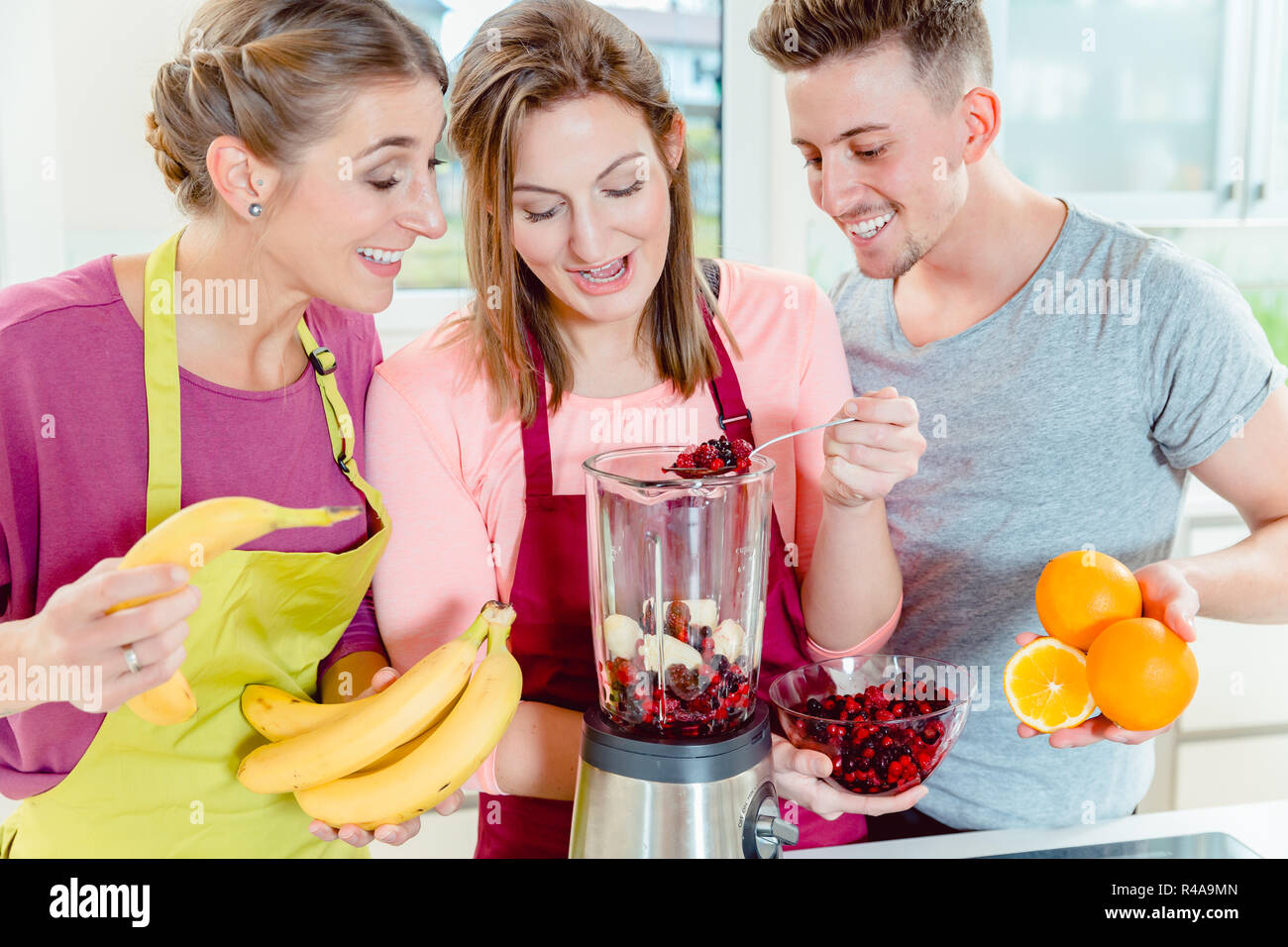 Donna aggiungendo le bacche nel bicchiere del frullatore Foto Stock
