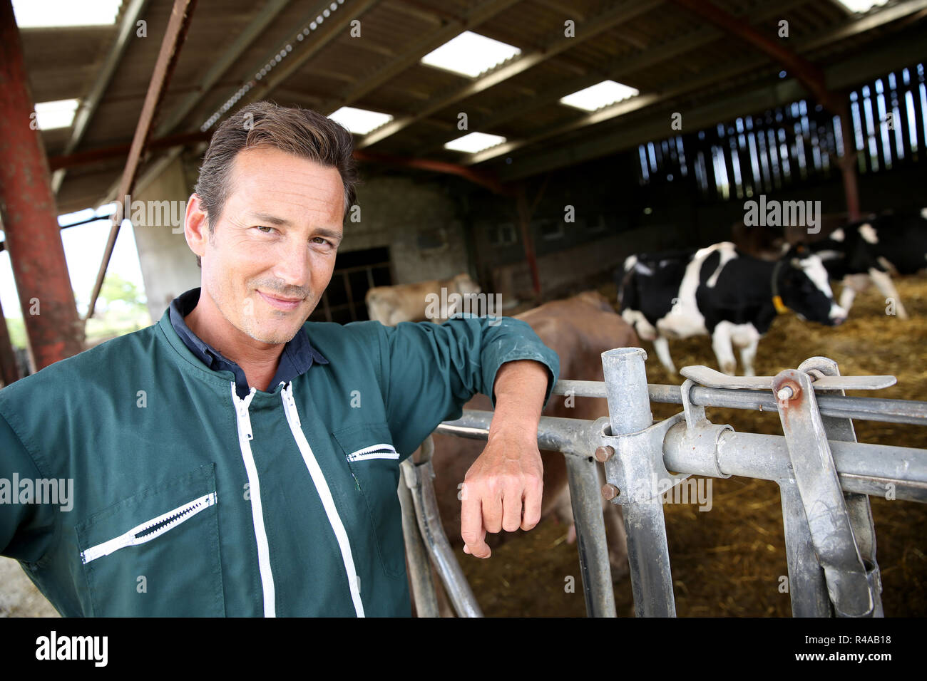 L'agricoltore sorridente in piedi nel fienile Foto Stock