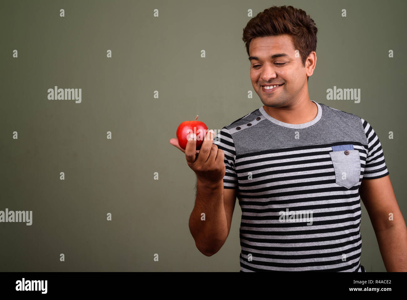 Indian uomo indossa camicia a righe e contenimento di frutta apple Foto Stock