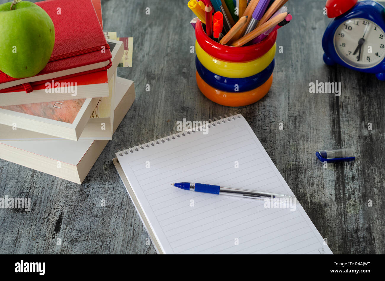 Libri di testo,pen,matite,notebook e orologio sono sul tavolo di legno. Lezione il concetto di studio Foto Stock