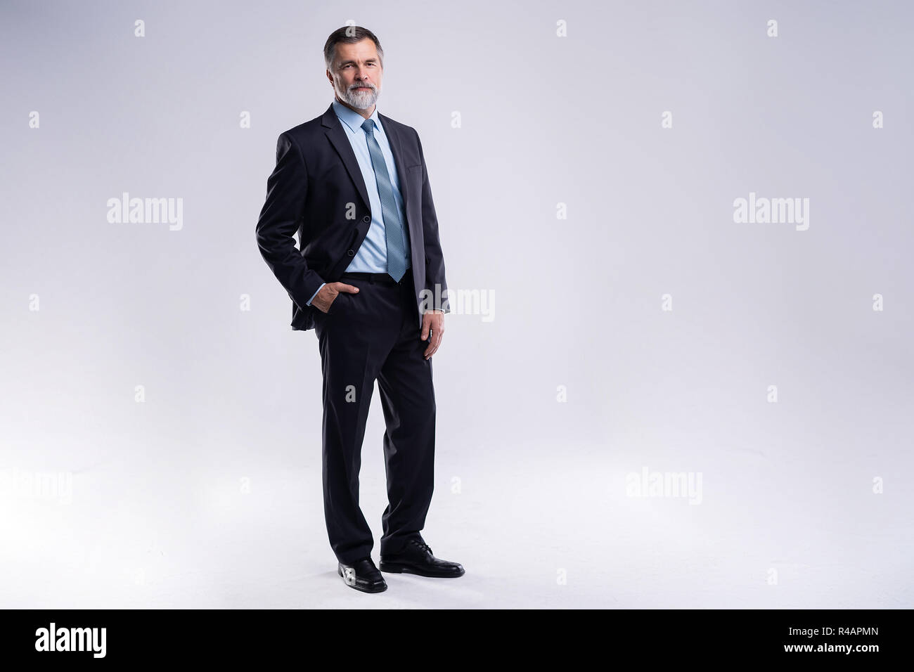 A piena lunghezza Ritratto di fiducioso imprenditore maturo in formali in piedi isolato su sfondo bianco. Foto Stock
