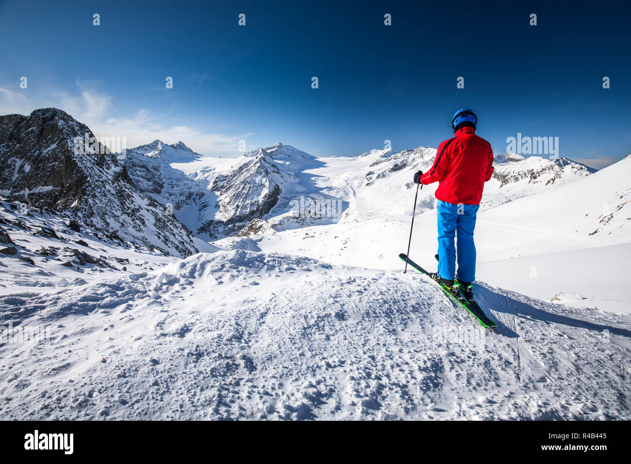 Giovani felici attraente sciatore sulla cima delle montagne godendo la vista dal ghiacciaio Presena, Tonale, Italia. Foto Stock