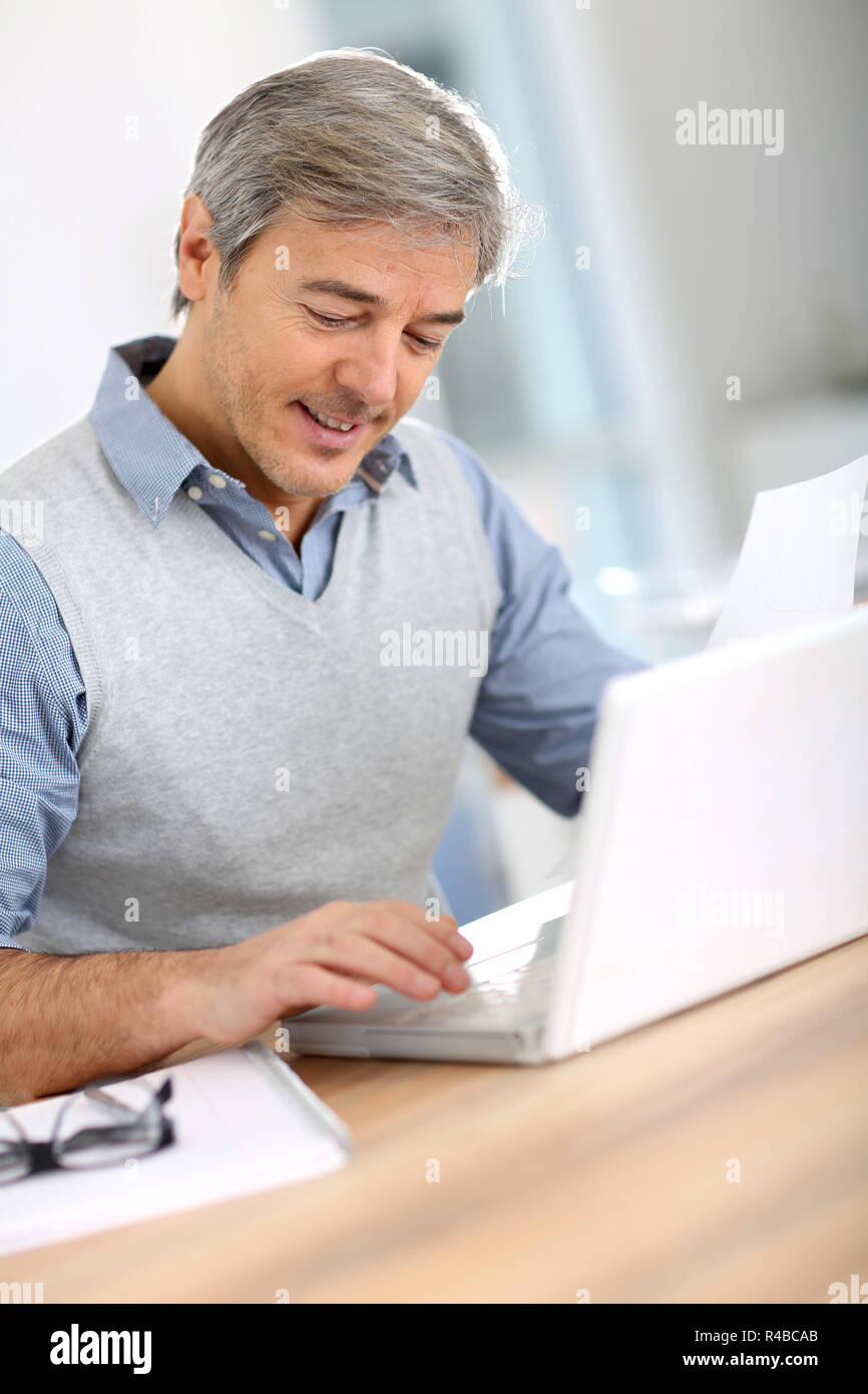 Imprenditore Senior in ufficio a lavorare sul computer portatile Foto Stock