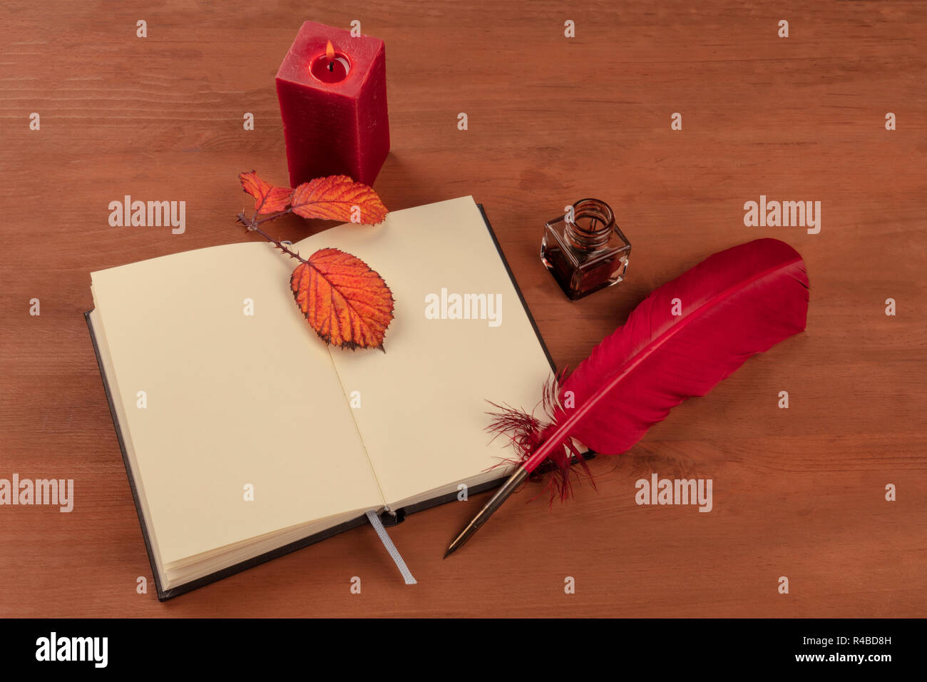 La poesia di scrittura. La foto di un cappello rosso con inchiostro e bene e un notebook aperto su una scrivania di legno con colori intensi e di foglie di autunno e una candela accesa Foto Stock