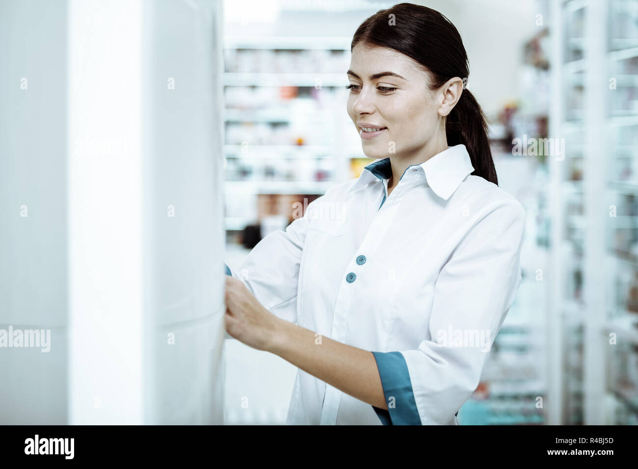 Mettere in ordine. Ragazza accurate indossando uniforme medica mentre fissando le merci in shopwindow Foto Stock
