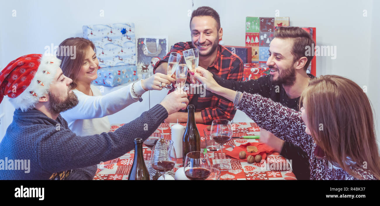 Happy amici per festeggiare il Natale e il nuovo anno a tavola a mangiare e bere Foto Stock