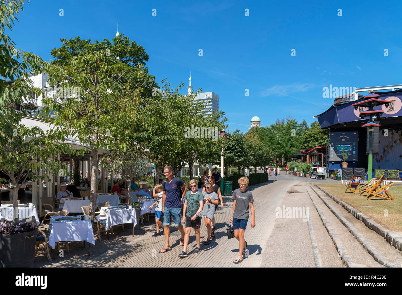 Famiglia camminare davanti a un ristorante presso i Giardini di Tivoli, Copenaghen, Zelanda, Danimarca Foto Stock