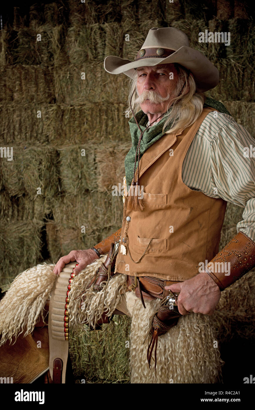 Autentico antico west cowboy ritratto con wooly chaps, pistola, cappello da cowboy, giubbotto in pelle, bandana ritratto in stabile Foto Stock