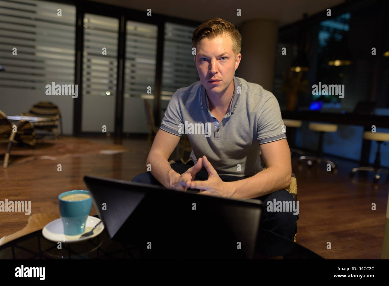 Giovane uomo bello utilizzando laptop nella stanza vivente Foto Stock